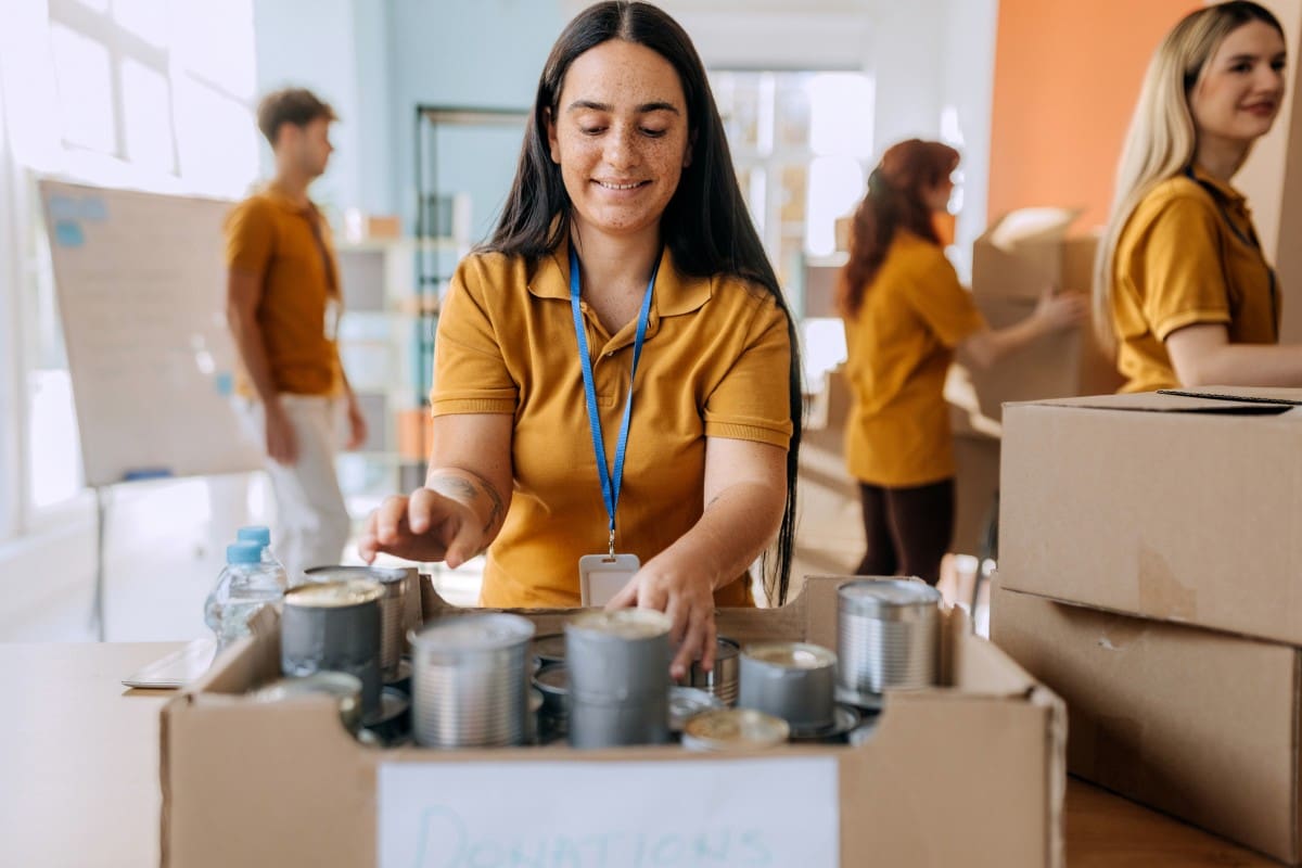 Volunteer organizing canned goods for donation.
