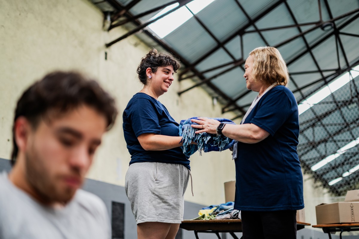 Two people folding clothes in warehouse.