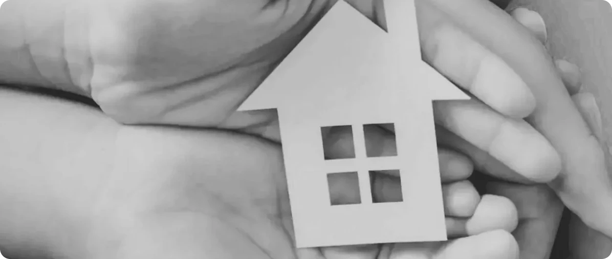 Hands holding a house-shaped paper cutout.
